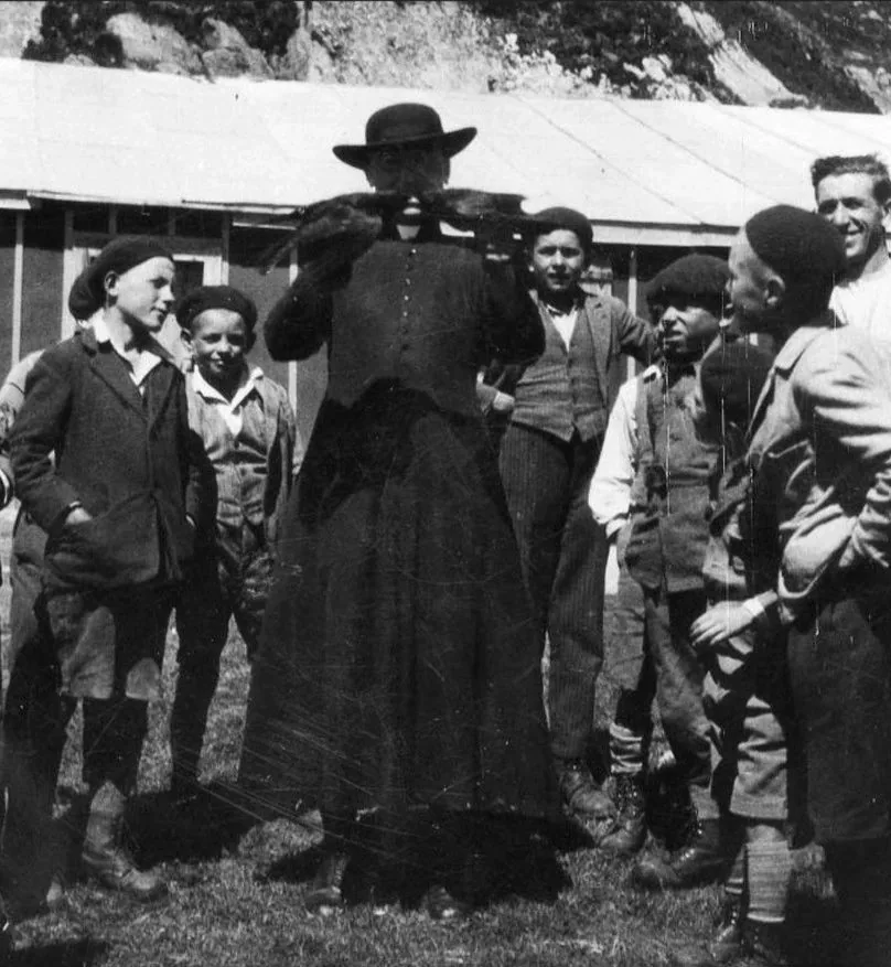 Fr. Henri Bonvin holding birds, and surrounded by children.